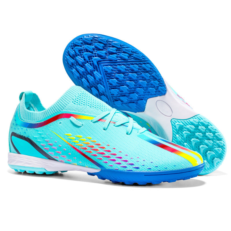Turquoise soccer shoes with blue soles on a white background
