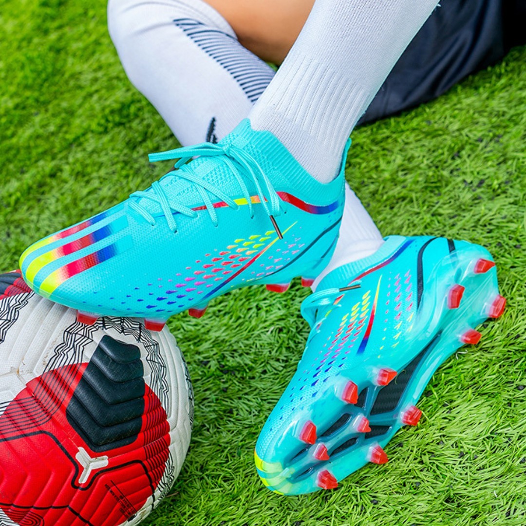 Turquoise soccer cleats with red studs on a grass field